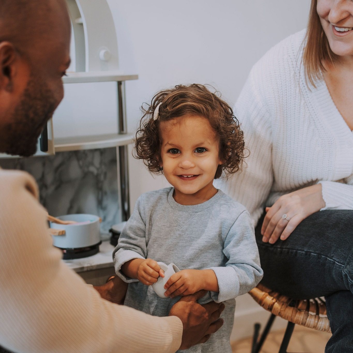 Un niño pequeño sonriendo con sus padres durante una visita familiar en illumINNATE Chiropractic Studio, Barcelona